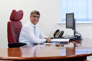 Smiling Heart of England Co-op chief executive Ali Kurji seated at desk