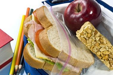 Sandwich, cereal bar and red apple in lunchbox with pencils