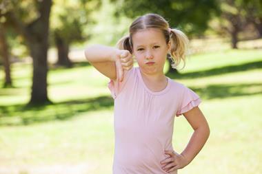 Girl stood in park wearing pink t-shirt and giving thumbs down