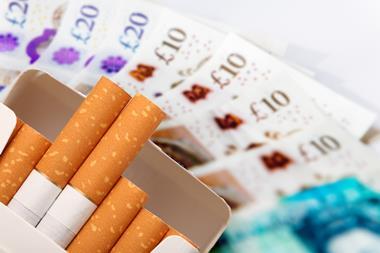 A packet of cigarettes set against a large amount of cash.