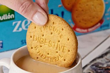 Hand dipping sugar free Zeroh Digestive biscuit into cup of tea