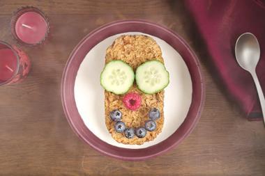 Smiley face made from cucumbers and berries on Weetabix in a cereal bowl