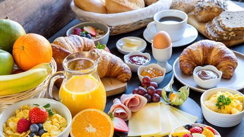 Vast array of breakfast foods including fruit, cereal and croissant.