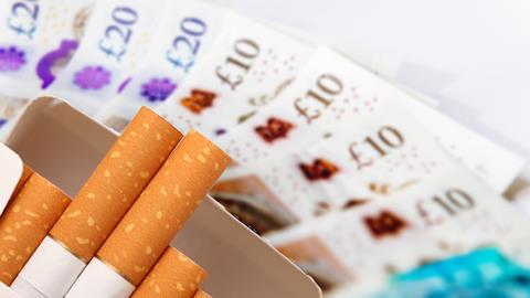 A packet of cigarettes set against a large amount of cash.