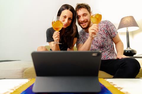 Couple enjoying cocktails whilst staying at home and watching lap top