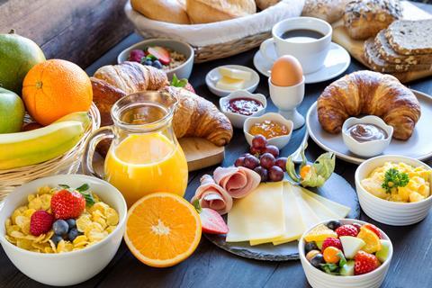 Vast array of breakfast foods including fruit, cereal and croissant.