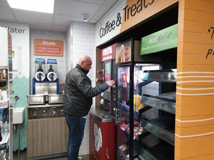 Man using a coffee machine in a convenience store