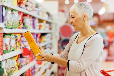 Older female shopper looking at cereal box