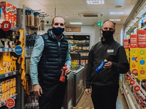Two men in Costcutter convenience store holding bottles of Boost drink