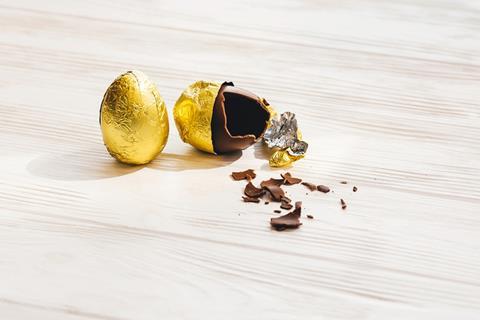 Broken Easter egg with chocolate pieces scattered on floor.