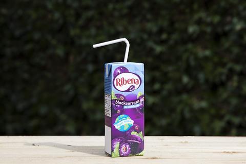 Ribena carton with paper straw instead of plastic on an outdoor wooden surface with green background