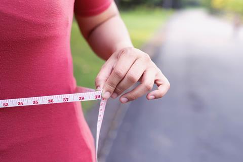 Woman holding measuring tape around waist.