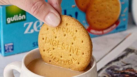 Hand dipping sugar free Zeroh Digestive biscuit into cup of tea