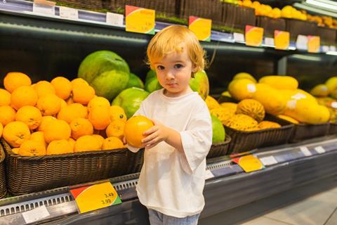 Small boy with fresh fruit in shop