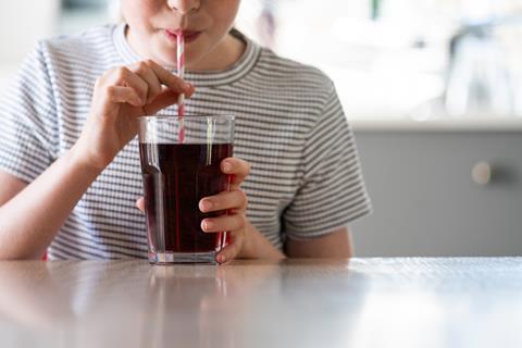 Child drinking cola through a straw at home