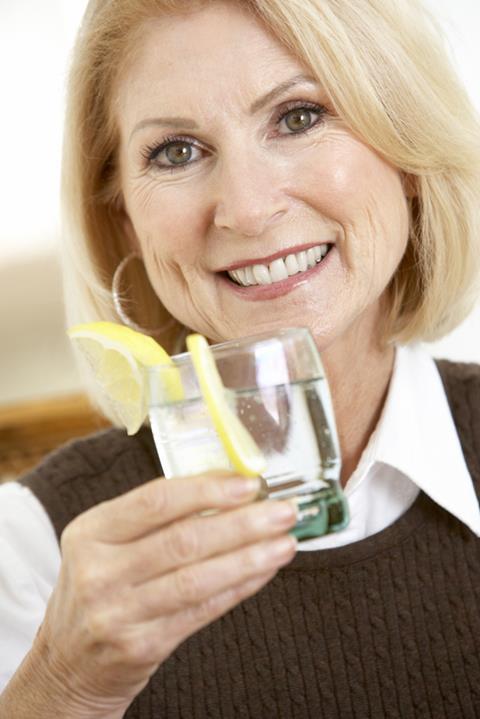Older woman holding glass of gin and tonic