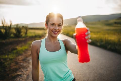 Sporty woman holding up sports drink while on a run