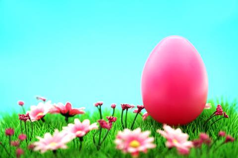 Large pink Easter egg on grass with pink flowers