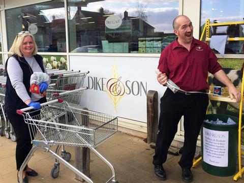 A customer wearing latex gloves waits to have her trolley sanitised by Adam Vincent