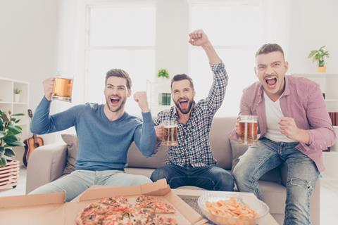 Three men watching sport on TV and drinking pints of beer