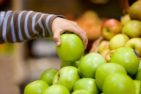 Hand reaching for apple from shop display