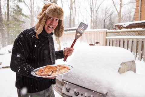 A man stood at a BBQ in bad weather